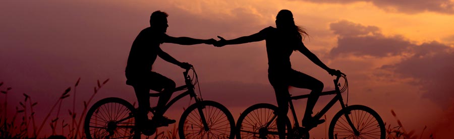 Two people riding bicycles and holding hands